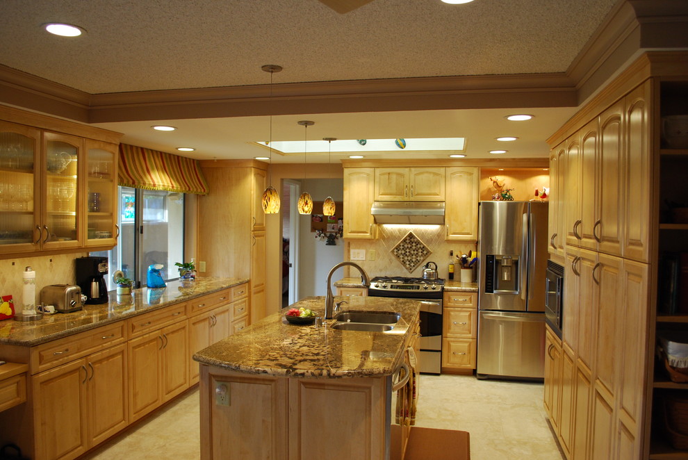 Traditional galley eat-in kitchen in Sacramento with an undermount sink, raised-panel cabinets, light wood cabinets, granite benchtops, beige splashback, stone tile splashback, stainless steel appliances, porcelain floors and with island.