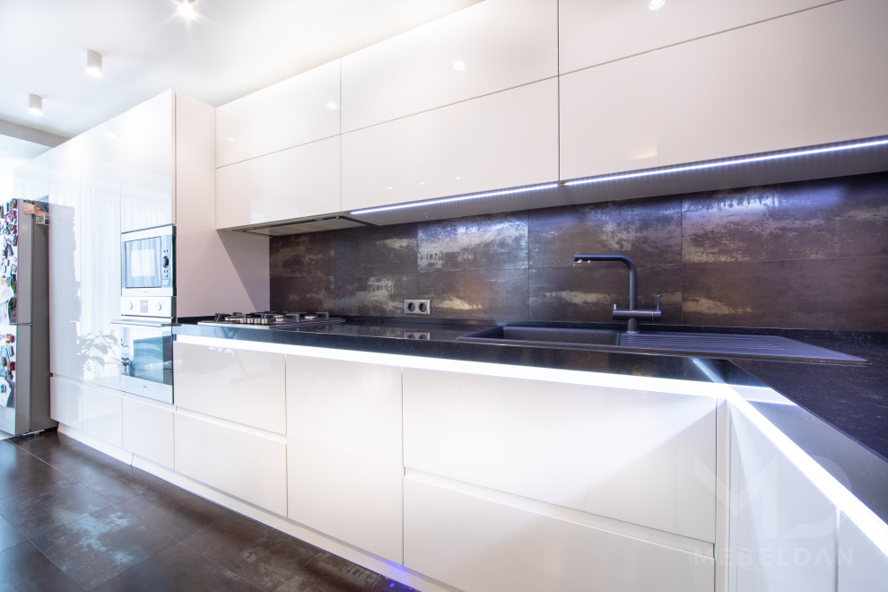 Inspiration for a mid-sized contemporary l-shaped eat-in kitchen in Other with a drop-in sink, white cabinets, quartzite benchtops, black splashback, ceramic splashback, black appliances, laminate floors, no island, beige floor and black benchtop.