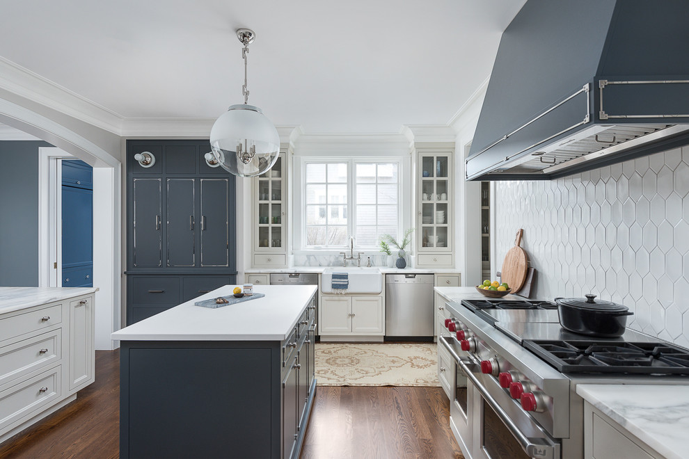 Inspiration for a transitional u-shaped eat-in kitchen in Chicago with a farmhouse sink, recessed-panel cabinets, blue cabinets, white splashback, stainless steel appliances, medium hardwood floors, multiple islands, brown floor and white benchtop.