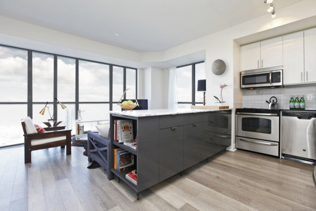 Photo of a small contemporary u-shaped open plan kitchen with flat-panel cabinets, grey cabinets, marble benchtops, with island, stainless steel appliances, an undermount sink, grey splashback, light hardwood floors and brown floor.
