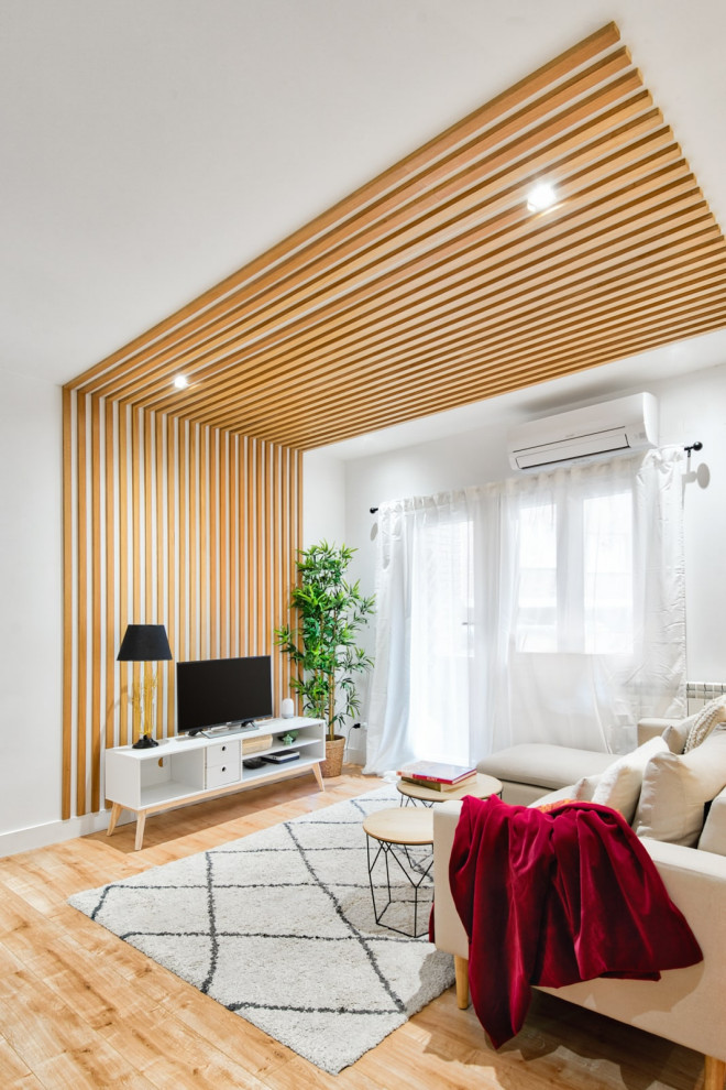 На фото: гостиная комната в белых тонах с отделкой деревом в скандинавском стиле с белыми стенами, деревянным потолком и панелями на части стены с