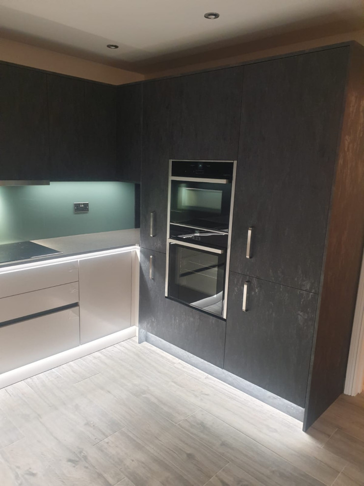Modern inredning av ett mellanstort grå grått kök, med bänkskiva i kvartsit, grönt stänkskydd, glaspanel som stänkskydd, rostfria vitvaror, vinylgolv, en köksö och grått golv