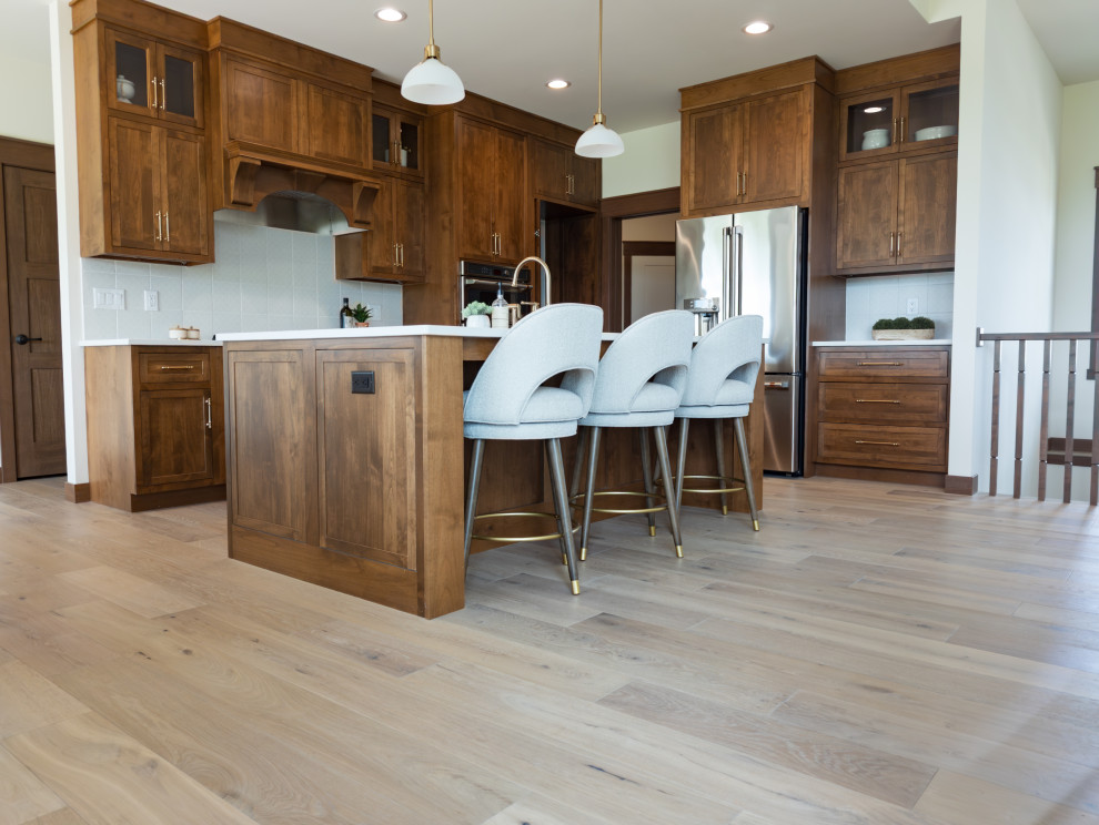 Example of a transitional galley light wood floor and beige floor open concept kitchen design with shaker cabinets, medium tone wood cabinets, quartz countertops, white backsplash, ceramic backsplash, an island and white countertops