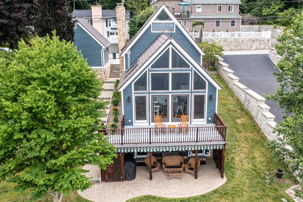 На фото: синий частный загородный дом среднего размера в классическом стиле с разными уровнями, комбинированной облицовкой, двускатной крышей, металлической крышей, коричневой крышей и отделкой планкеном