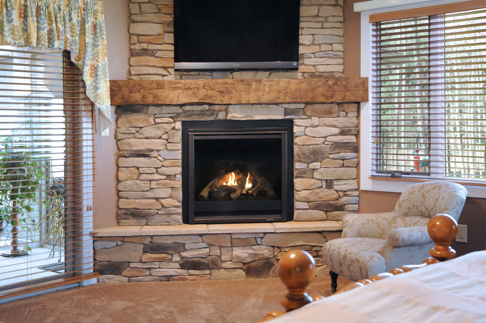 Photo of a mid-sized traditional master bedroom in Cleveland with beige walls, carpet, a corner fireplace, a stone fireplace surround and beige floor.