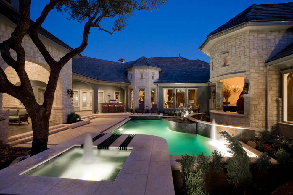 Design ideas for a mid-sized traditional courtyard custom-shaped pool in Austin with a water feature and decking.