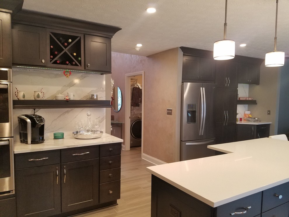 Example of a mid-sized transitional l-shaped porcelain tile and gray floor enclosed kitchen design with an undermount sink, raised-panel cabinets, dark wood cabinets, quartz countertops, white backsplash, stone slab backsplash, stainless steel appliances and an island