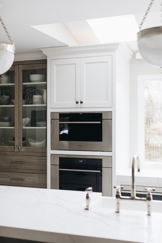 Mid-sized transitional dark wood floor and brown floor eat-in kitchen photo in Chicago with a farmhouse sink, beaded inset cabinets, white cabinets, quartz countertops, paneled appliances, an island and white countertops