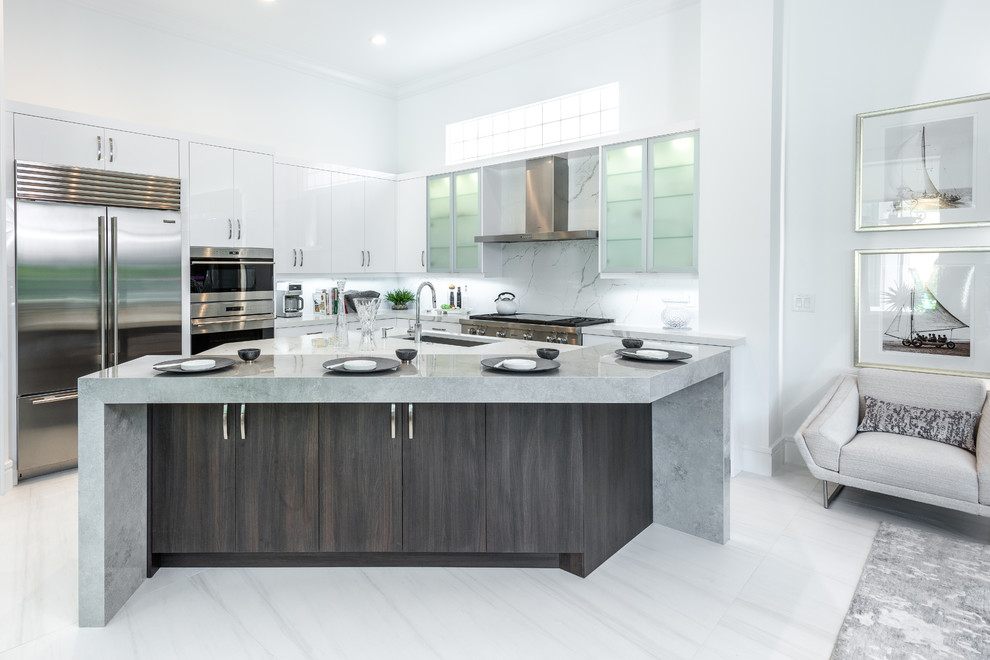 Contemporary kitchen in Miami with flat-panel cabinets, white cabinets, stainless steel appliances, with island, an undermount sink, white splashback, white floor and grey benchtop.