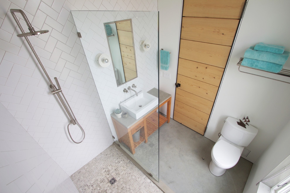 This is an example of a small modern bathroom in Providence with a vessel sink, open cabinets, medium wood cabinets, concrete benchtops, an alcove shower, a two-piece toilet, white tile, ceramic tile, white walls and concrete floors.