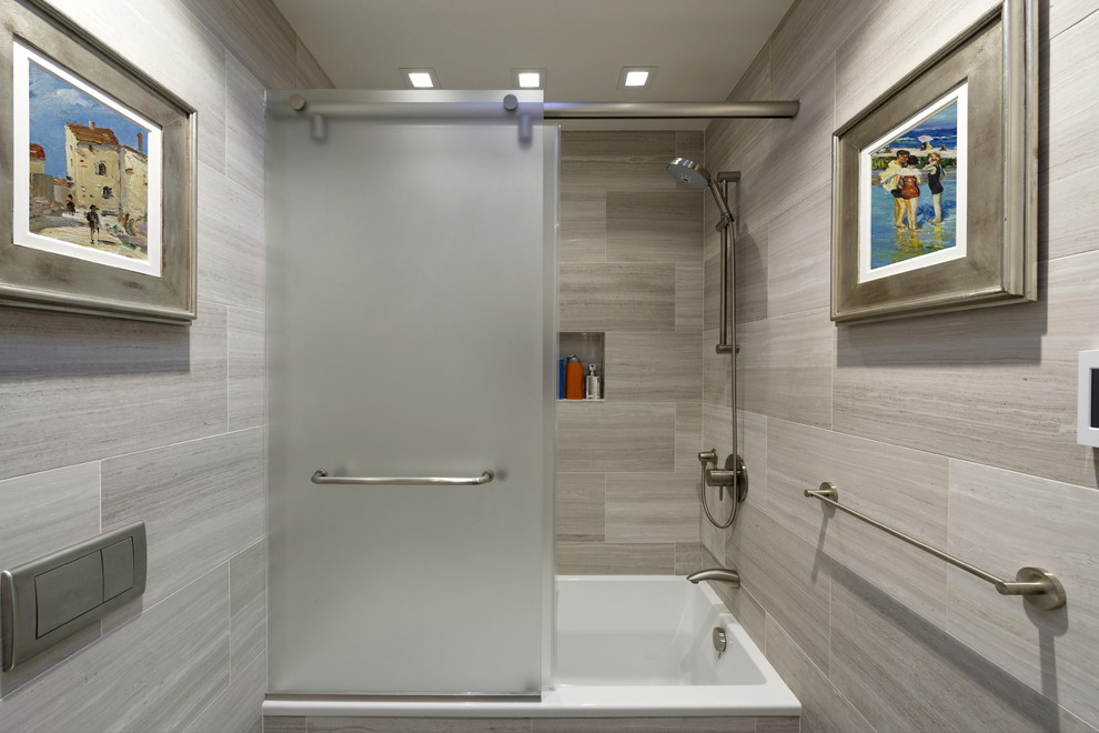 Mid-sized contemporary kids bathroom in DC Metro with furniture-like cabinets, medium wood cabinets, an alcove tub, a shower/bathtub combo, a wall-mount toilet, gray tile, marble, grey walls, slate floors, a vessel sink, limestone benchtops, black floor, a sliding shower screen and grey benchtops.