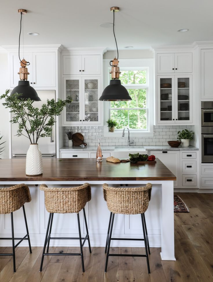 Photo of a large country single-wall open plan kitchen in Columbus with a farmhouse sink, flat-panel cabinets, white cabinets, marble benchtops, white splashback, subway tile splashback, stainless steel appliances, medium hardwood floors, with island, brown floor and white benchtop.