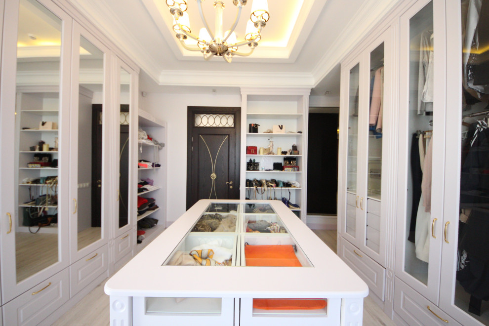 Photo of a large eclectic women's walk-in wardrobe in Moscow with recessed-panel cabinets, light wood cabinets, medium hardwood floors, beige floor and recessed.