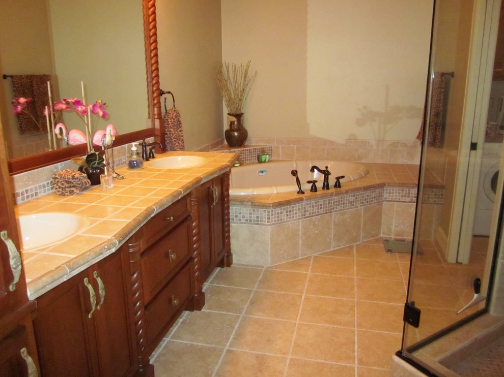 This is an example of a mid-sized mediterranean 3/4 bathroom in Milwaukee with raised-panel cabinets, dark wood cabinets, a drop-in tub, an open shower, a one-piece toilet, beige tile, stone tile, beige walls, ceramic floors, a drop-in sink and tile benchtops.