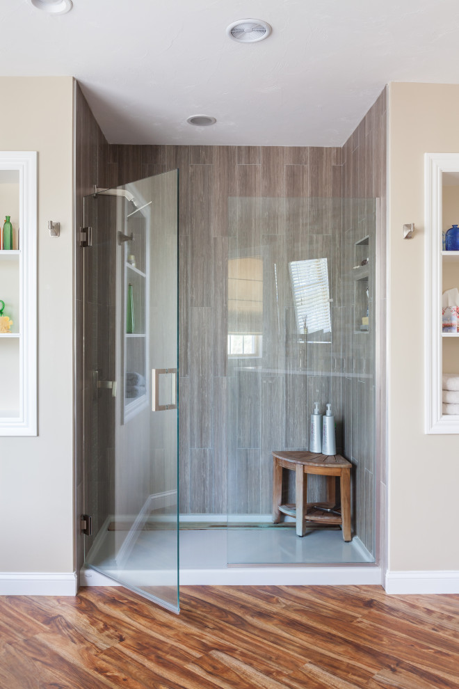 Inspiration for a large modern master bathroom in Boston with flat-panel cabinets, dark wood cabinets, a freestanding tub, an alcove shower, beige tile, stone tile, beige walls, medium hardwood floors, an undermount sink and a hinged shower door.