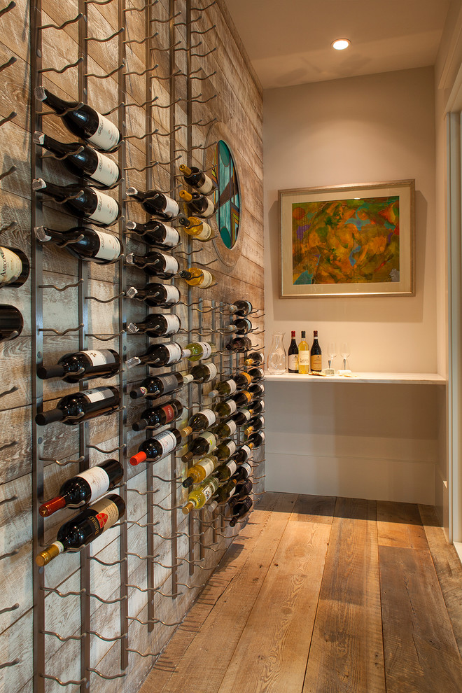 Design ideas for a large beach style wine cellar in Other with painted wood floors, storage racks and brown floor.