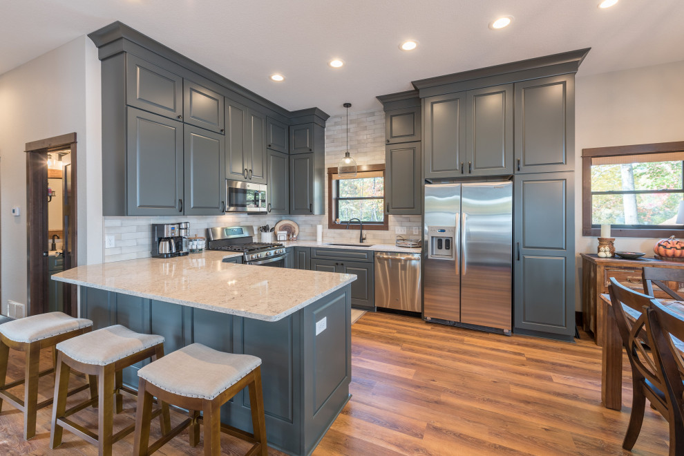 Large transitional u-shaped eat-in kitchen in Minneapolis with an undermount sink, raised-panel cabinets, green cabinets, quartz benchtops, beige splashback, subway tile splashback, stainless steel appliances, linoleum floors, a peninsula, brown floor and beige benchtop.