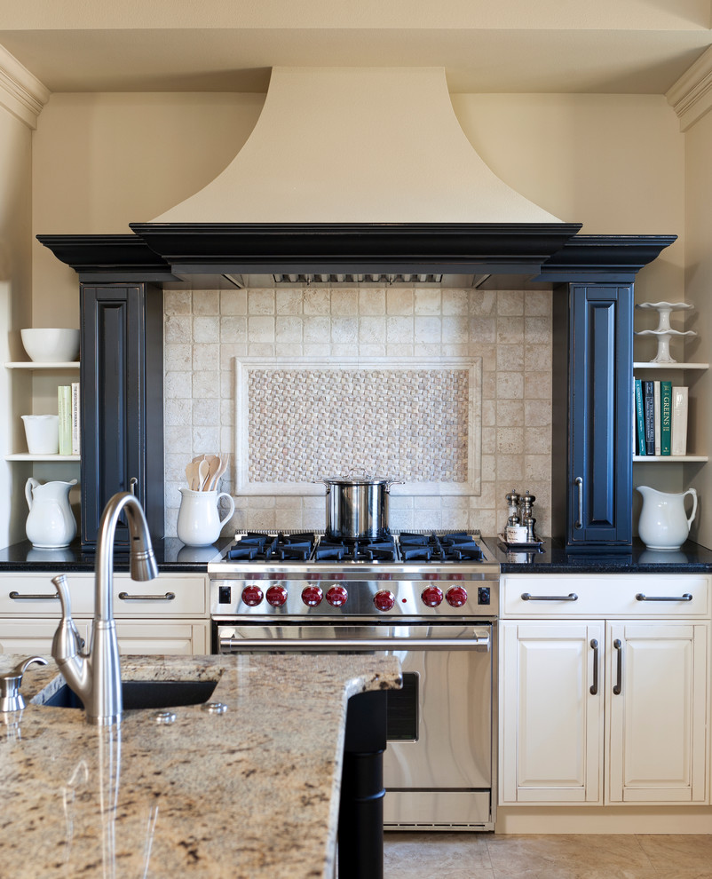 Example of a classic u-shaped ceramic tile kitchen design with an undermount sink, raised-panel cabinets, black cabinets, granite countertops, beige backsplash, ceramic backsplash, stainless steel appliances and an island