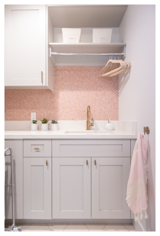 This is an example of a mid-sized eclectic l-shaped dedicated laundry room in Phoenix with an undermount sink, shaker cabinets, grey cabinets, quartz benchtops, pink splashback, ceramic splashback, white walls, porcelain floors, a side-by-side washer and dryer, white floor and white benchtop.