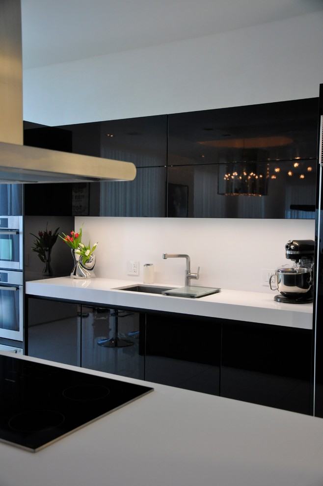 Inspiration for a mid-sized modern u-shaped eat-in kitchen in Miami with an undermount sink, flat-panel cabinets, black cabinets, quartz benchtops, white splashback, stone slab splashback, stainless steel appliances, marble floors and with island.
