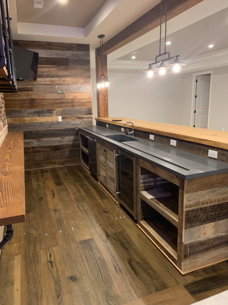 This is an example of a large country single-wall seated home bar in Detroit with an undermount sink, white cabinets, wood benchtops, multi-coloured splashback, brick splashback, medium hardwood floors, brown floor and beige benchtop.