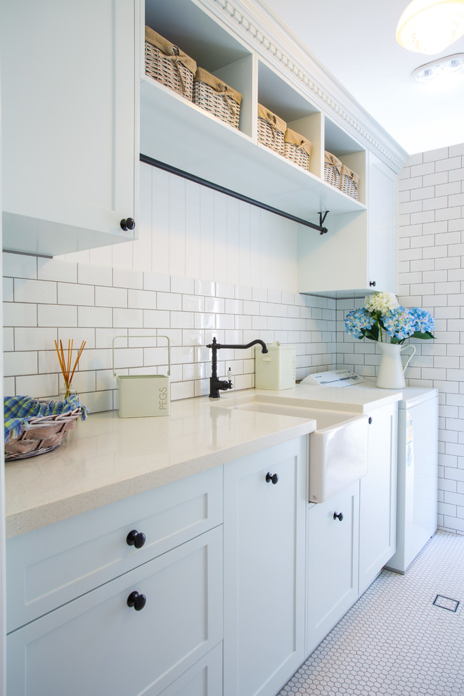 This is an example of a large traditional laundry room in Canberra - Queanbeyan with a farmhouse sink, shaker cabinets, white cabinets, quartz benchtops, white walls and ceramic floors.