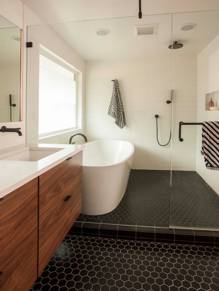 Mid-sized midcentury master wet room bathroom in Seattle with open cabinets, a freestanding tub, a one-piece toilet, white tile, ceramic tile, white walls, porcelain floors, an integrated sink, quartzite benchtops, black floor, a hinged shower door and white benchtops.