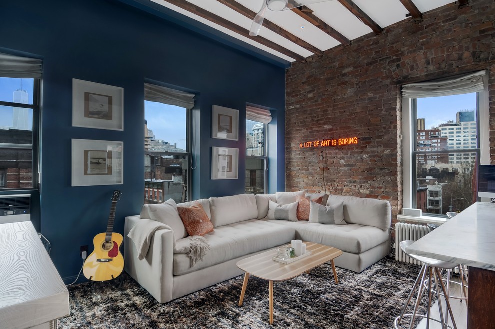 This is an example of a small transitional loft-style living room in New York with a music area, blue walls, dark hardwood floors and a wall-mounted tv.