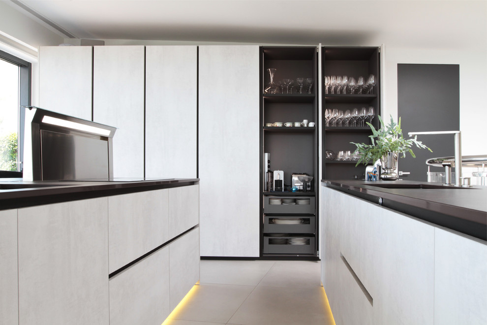 Design ideas for a large modern single-wall open plan kitchen in Other with flat-panel cabinets, grey cabinets, black splashback, ceramic splashback, stainless steel appliances, porcelain floors, multiple islands, grey floor and black benchtop.