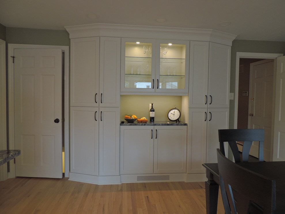 Kitchen - transitional light wood floor kitchen idea with a single-bowl sink, shaker cabinets, white cabinets, granite countertops, white backsplash, ceramic backsplash, stainless steel appliances, an island and black countertops