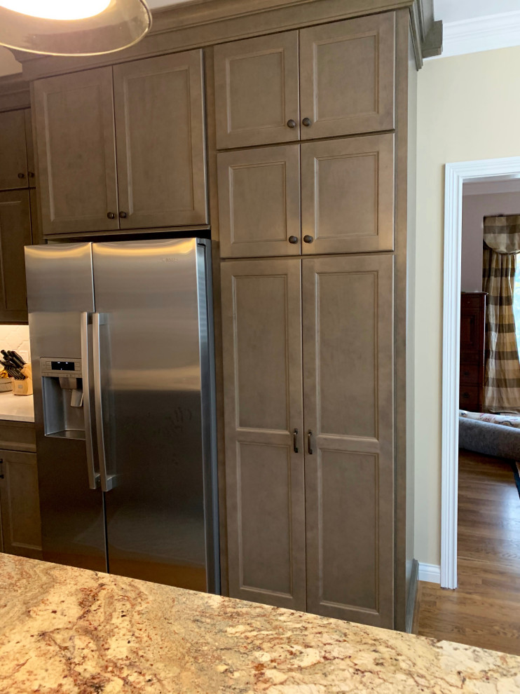 Example of a mid-sized transitional l-shaped medium tone wood floor and brown floor eat-in kitchen design in Cincinnati with an undermount sink, recessed-panel cabinets, gray cabinets, quartz countertops, white backsplash, porcelain backsplash, stainless steel appliances, an island and white countertops