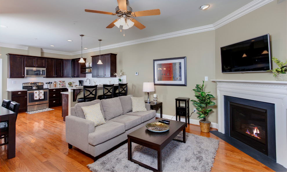 This is an example of a small traditional open concept family room in Bridgeport with beige walls, medium hardwood floors, a standard fireplace, a tile fireplace surround, a wall-mounted tv and brown floor.