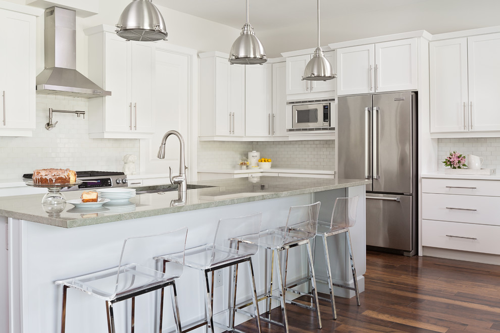 Transitional l-shaped kitchen in Los Angeles with an undermount sink, shaker cabinets, white cabinets, white splashback, subway tile splashback, stainless steel appliances, dark hardwood floors, with island and grey benchtop.