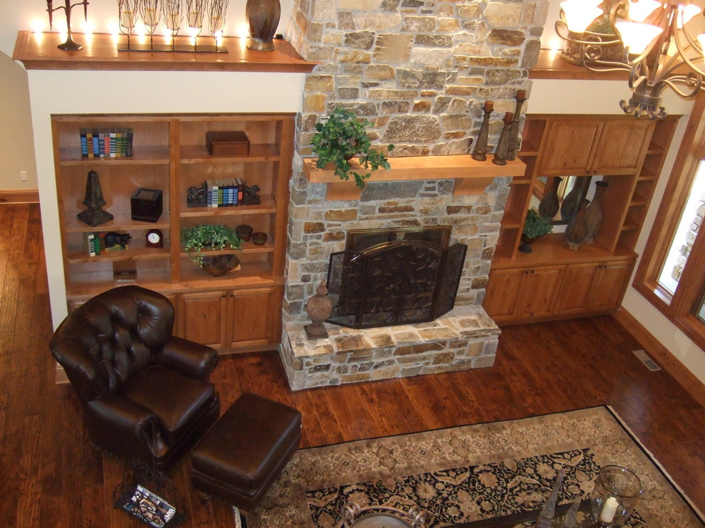 This is an example of a mid-sized traditional enclosed family room in Seattle with beige walls, dark hardwood floors, a standard fireplace, a stone fireplace surround, no tv and brown floor.