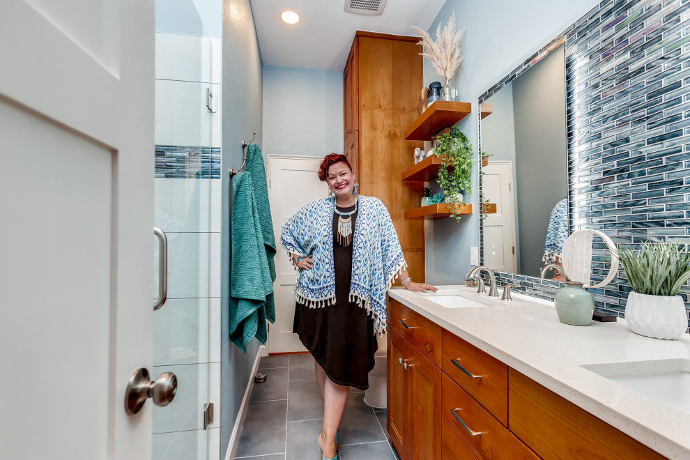 This is an example of a medium sized nautical family bathroom in Dallas with shaker cabinets, medium wood cabinets, an alcove shower, a two-piece toilet, multi-coloured tiles, porcelain tiles, blue walls, porcelain flooring, a submerged sink, engineered stone worktops, grey floors, a hinged door, white worktops, a wall niche, double sinks and a freestanding vanity unit.