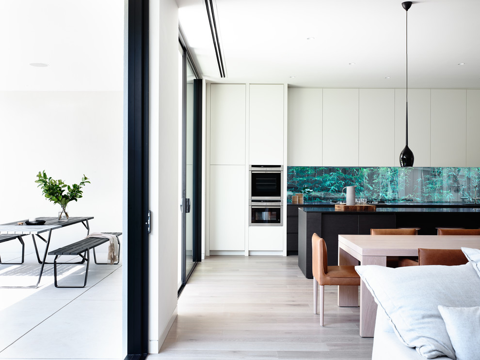Photo of a modern kitchen in Melbourne with glass sheet splashback and with island.