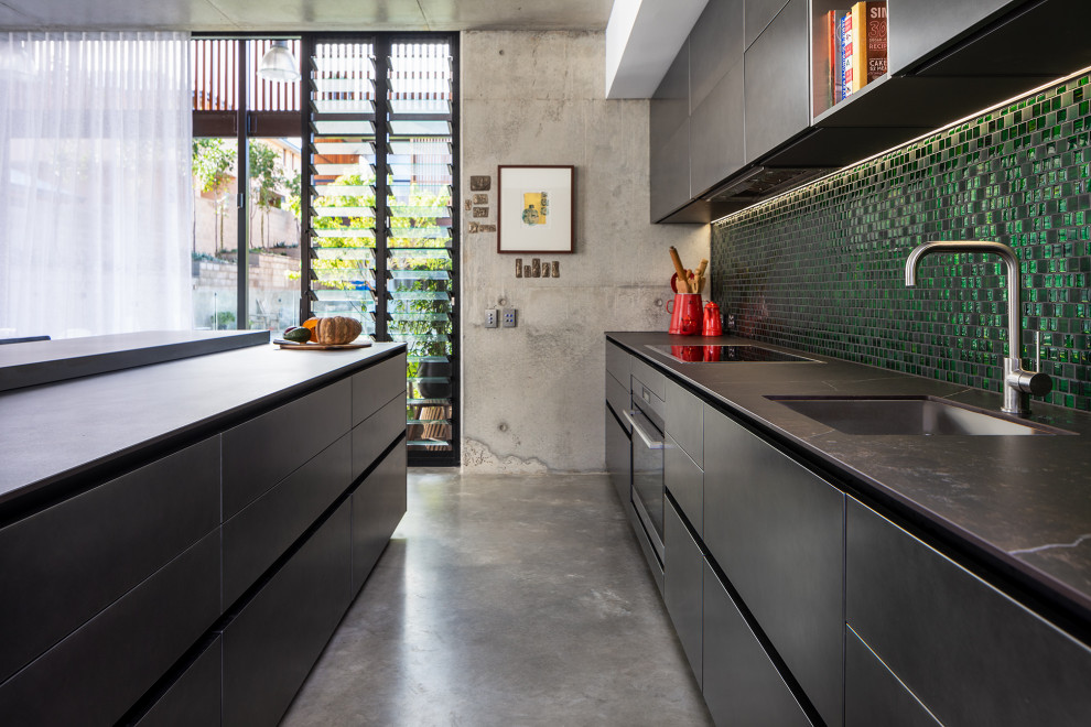 Photo of a large eclectic open plan kitchen in Perth with an undermount sink, green splashback, glass tile splashback, panelled appliances, concrete floors, with island and grey benchtop.