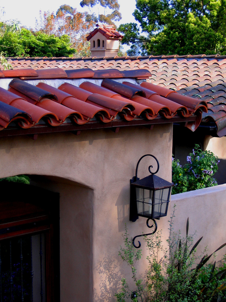 Photo of a mid-sized mediterranean one-storey stucco beige house exterior in Santa Barbara with a clipped gable roof and a tile roof.