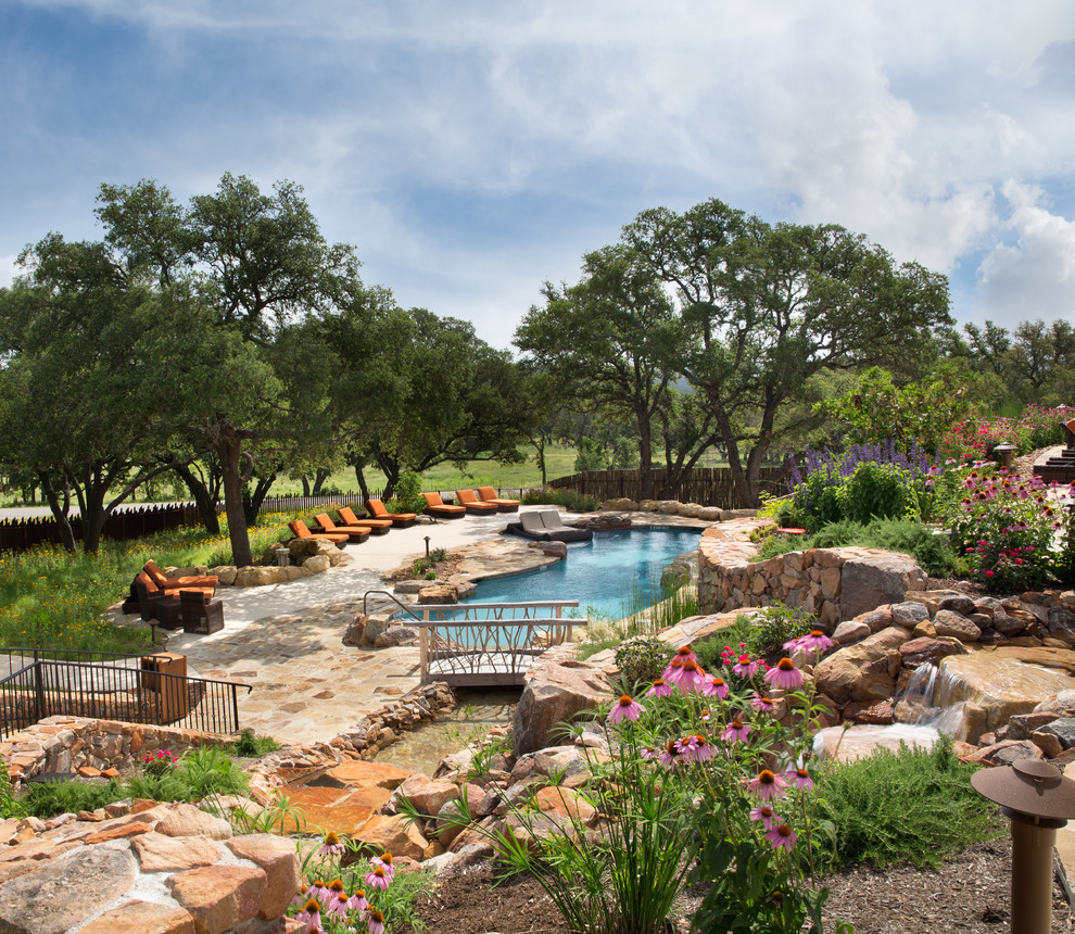 Inspiration for an expansive country backyard custom-shaped pool in Austin with natural stone pavers.