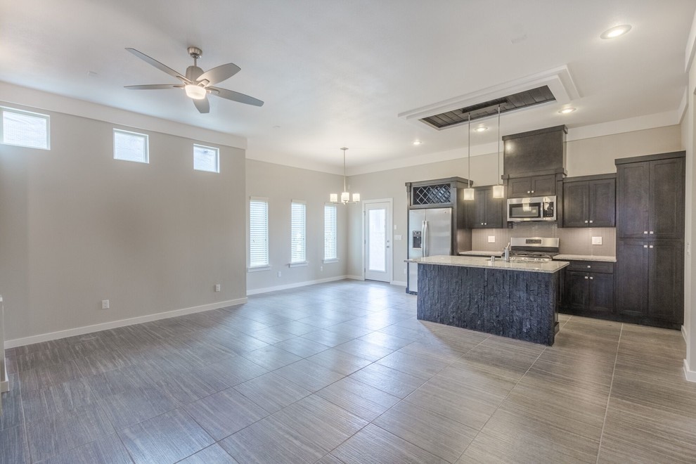 Mid-sized transitional ceramic tile home design photo in Austin with a double-bowl sink, flat-panel cabinets, dark wood cabinets, granite countertops, white backsplash, glass tile backsplash, stainless steel appliances and an island