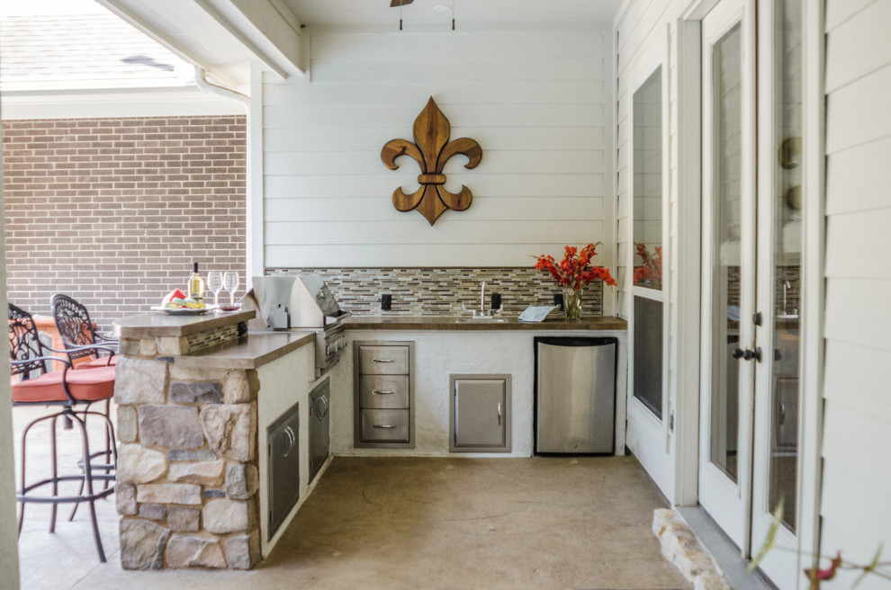 Design ideas for a traditional backyard patio in Dallas with an outdoor kitchen, concrete slab and a roof extension.