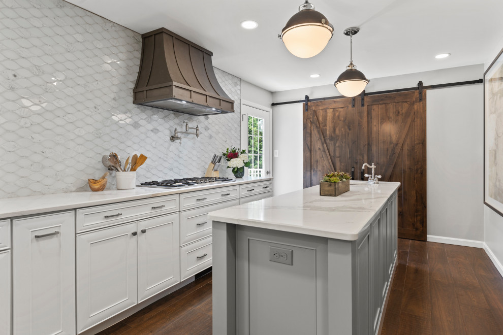 Example of a mid-sized transitional single-wall dark wood floor and brown floor eat-in kitchen design in DC Metro with a farmhouse sink, recessed-panel cabinets, white cabinets, quartzite countertops, white backsplash, glass tile backsplash, stainless steel appliances, two islands and white countertops
