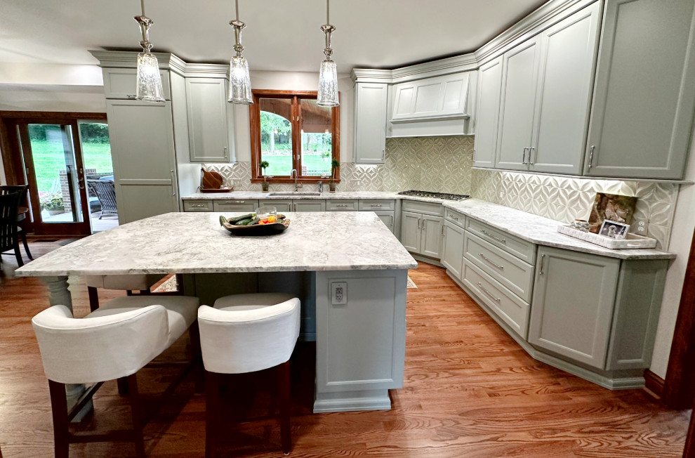 Transitional l-shaped medium tone wood floor eat-in kitchen photo with shaker cabinets, green cabinets, quartzite countertops, porcelain backsplash, paneled appliances and an island