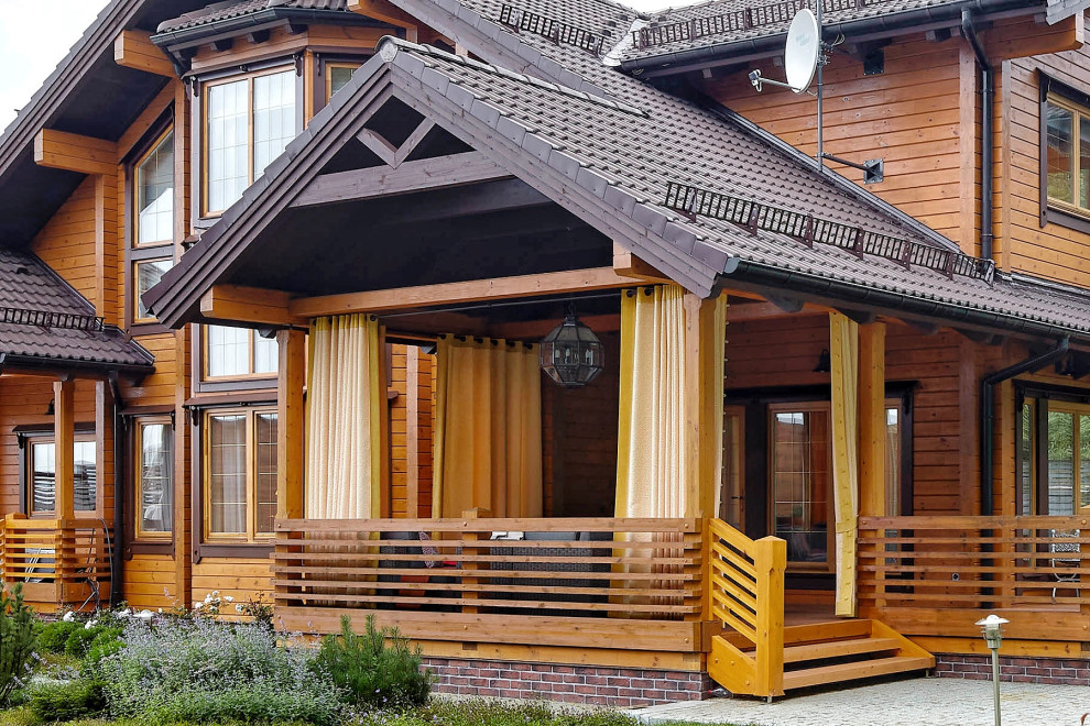 Inspiration for a mid-sized country courtyard and ground level deck in Moscow with a roof extension and wood railing.