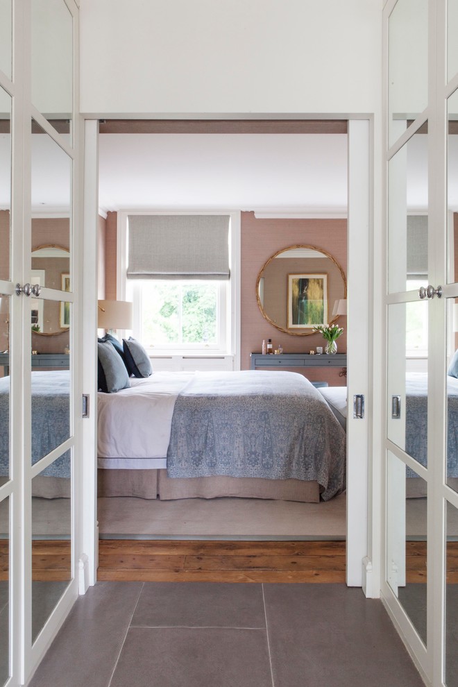 Design ideas for a traditional master bedroom in London with pink walls, medium hardwood floors and no fireplace.
