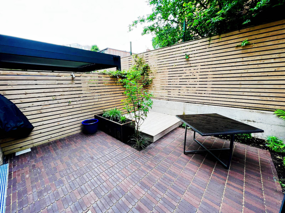 Photo of a small contemporary courtyard patio in London with fencing and natural stone paving.