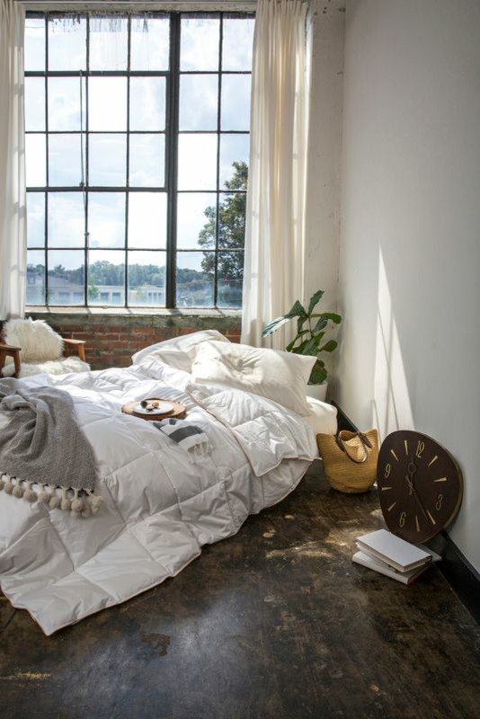 This is an example of a mid-sized modern loft-style bedroom in New York with white walls and concrete floors.