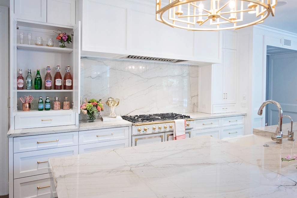 Open concept kitchen - large transitional l-shaped medium tone wood floor and brown floor open concept kitchen idea with a farmhouse sink, recessed-panel cabinets, white cabinets, quartzite countertops, white backsplash, stone slab backsplash, paneled appliances and an island