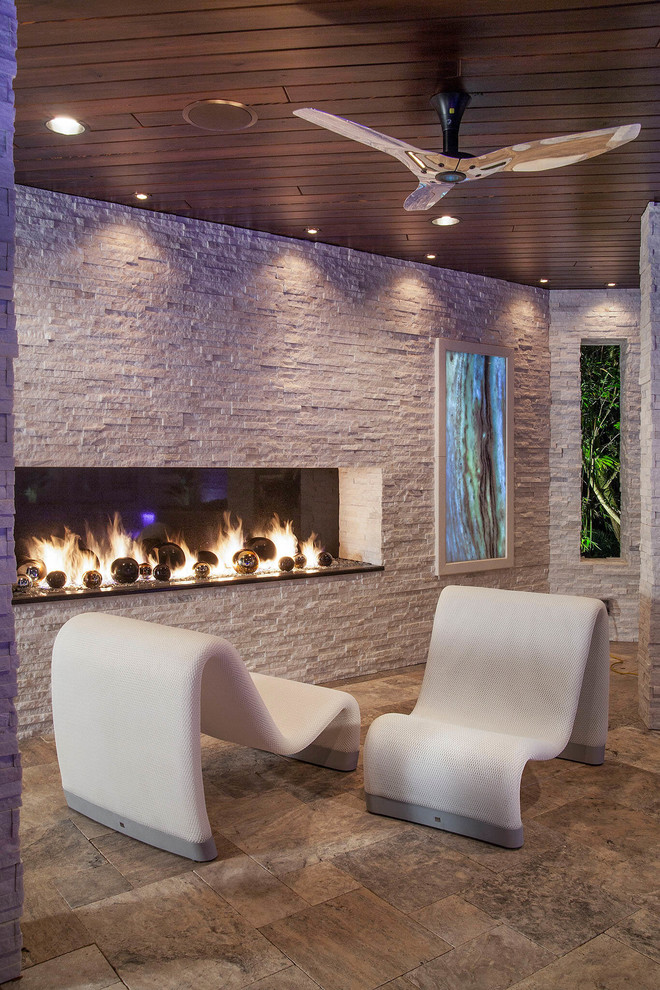 Inspiration for a large modern backyard patio in Tampa with a fire feature, natural stone pavers and a roof extension.