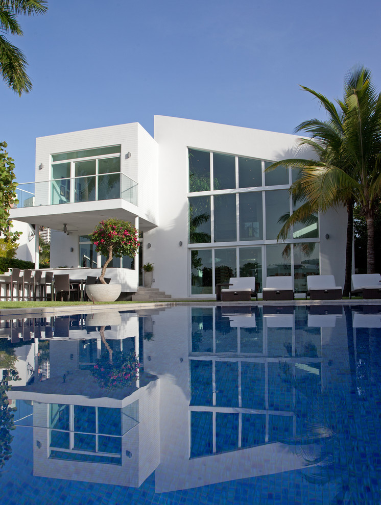 Photo of a large contemporary backyard rectangular lap pool in Miami with concrete pavers.